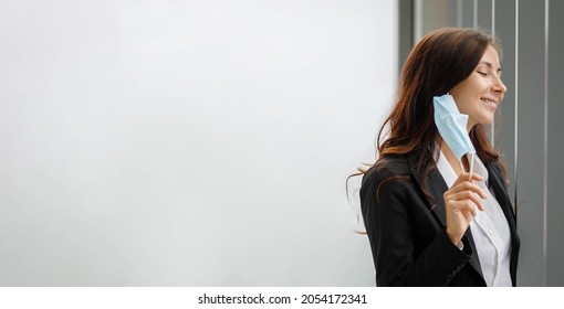 Happy Caucasian Businesswoman Employee Officer Staff In Formal Suit Standing Smiling Alone Taking Off Hygiene Safety Protective Face Mask Breathing Free. Social Distancing Freedom In Company Office.