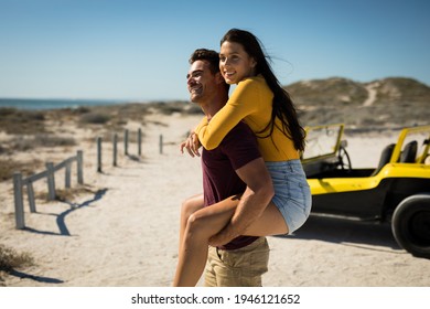 Happy caucasian couple next to beach buggy by the sea piggybacking. beach break on summer holiday road trip. - Powered by Shutterstock