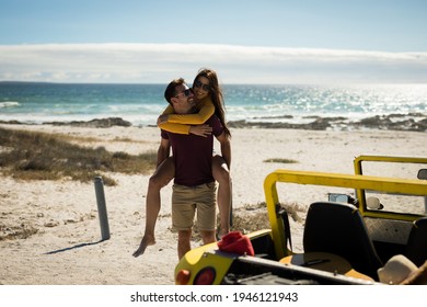 Happy caucasian couple next to beach buggy by the sea piggybacking. beach break on summer holiday road trip. - Powered by Shutterstock