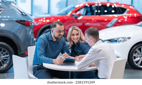 Happy caucasian couple signs a contract for the purchase of a car salon. - Powered by Shutterstock