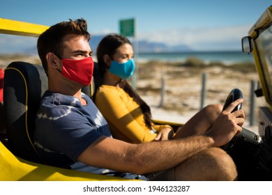 Happy Caucasian Couple Wearing Face Masks Sitting In Beach Buggy. Beach Stop Off On Summer Holiday Road Trip During Coronavirus Covid 19 Pandemic.