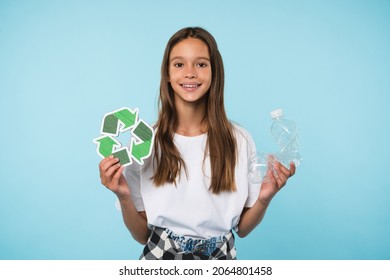 Happy caucasian eco-activist student schoolgirl pupil holding recycling logo sign and plastic bottle for environment protection, sorting garbage isolated in blue background - Powered by Shutterstock