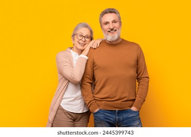 Happy Caucasian elderly couple embraces against yellow studio backdrop, radiating love and warmth of longlasting marriage. Concept of mature affection and enduring companionship - Powered by Shutterstock