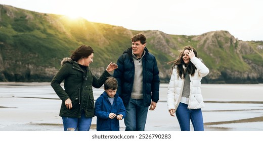 Happy Caucasian family at the beach, mother, father, son, and daughter. Happy family enjoys a beach day. Family time at the beach. Family trip at beach in winter costume. Parent trip in winter. - Powered by Shutterstock