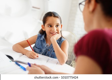 Happy caucasian family at home. Hispanic mother and female child. Latina mom helping daughter with school homework. Education, people, motherhood and relationship, woman teaching and girl learning