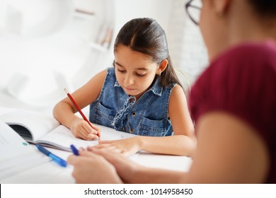 Happy Caucasian Family At Home. Hispanic Mother And Female Child. Latina Mom Helping Daughter With School Homework. Education, People, Motherhood And Relationship, Woman Teaching And Girl Learning