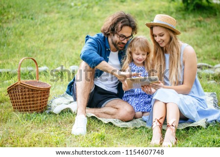 happy caucasian Family sitting in garden watching tablet