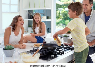 Happy caucasian family standing around stove, son making pancakes on stove - Powered by Shutterstock