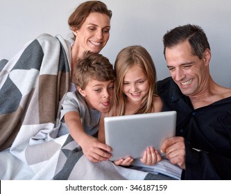 Happy Caucasian Family With Two Kids Spending Quality Time Internet Video Call On Tablet Device At Home