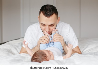 Happy Caucasian Father Holding Newborn Baby. Male Bearded Man Parent Hugging Kissing His Child Daughter Son Feet. Authentic Lifestyle Candid Moment. Proud Young Dad. Family Fathers Day.