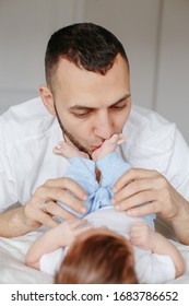 Happy Caucasian Father Holding Newborn Baby. Male Bearded Man Parent Hugging Kissing His Child Daughter Son Feet. Authentic Lifestyle Candid Moment. Proud Young Dad. Family Fathers Day.