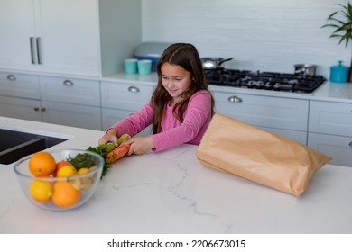 Happy Caucasian Girl Unpacking Groceries In Kitchen. Childhood, Leisure And Spending Free Time At Home.