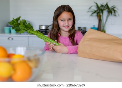 Happy Caucasian Girl Unpacking Groceries In Kitchen. Childhood, Leisure And Spending Free Time At Home.