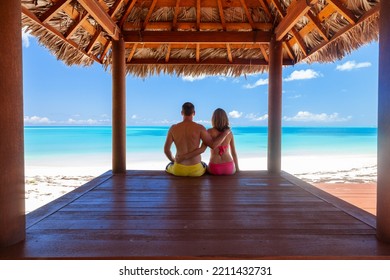 Happy Caucasian male and female in tropical bamboo hut enjoying holiday and sea view on the beach outdoor Caribbean - Powered by Shutterstock