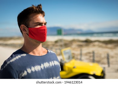 Happy caucasian man wearing face mask next to beach buggy looking toward sea. beach stop off on summer holiday road trip during coronavirus covid 19 pandemic. - Powered by Shutterstock