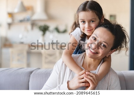 Happy caucasian mother and cute little daughter girl hugging embracing , spending time together looking at camera at home. Love and care, family moments, parenthood and motherhood concept