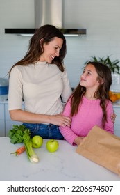 Happy Caucasian Mother And Daughter Unpacking Groceries In Kitchen. Family Time, Having Fun Together At Home.