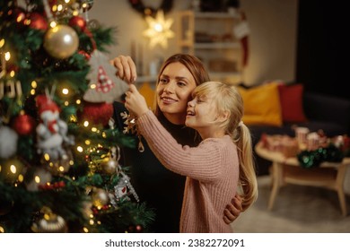 Happy Caucasian mother and her daughter are in their home during Christmas,  decorating a Christmas tree and having fun - Powered by Shutterstock