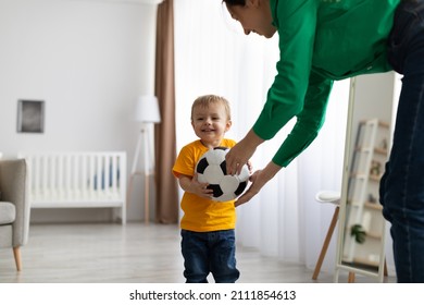 Happy caucasian mother and her toddler son playing with soccer ball at home, having fun and enjoying time together, free space. Maternity leave, childhood and leisure time concept
