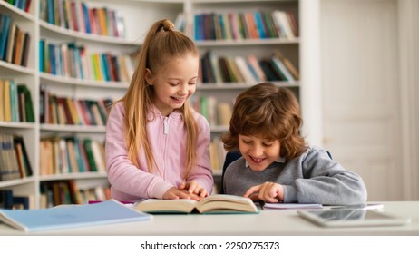 Happy caucasian primary school children reading book together in school library, sitting at table and smiling, panorama. Education, kid and study concept - Powered by Shutterstock