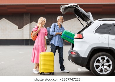 Happy caucasian senior couple going car trip together. Cheerful elderly man and woman in casual travelers getting ready before journey by auto, loading vehicle trunk with luggage, stand outdoors - Powered by Shutterstock