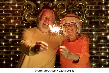 Happy caucasian senior couple holding sparklers celebrating new year. Joyful lifestyle for mature retirees, party lights - Powered by Shutterstock