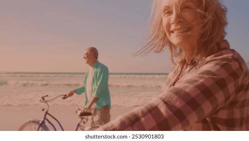 Happy caucasian senior couple riding bicycles together at the beach. Travel vacation retirement lifestyle concept - Powered by Shutterstock