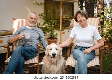 Happy caucasian senior family couple spouses relaxing on the yard of trailer camper van motor home together with dog domestic animal labrador golden retriever - Powered by Shutterstock