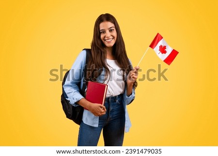 Happy caucasian teenager student woman, with Canada flag and book, enjoy exchange study, isolated on yellow background. Lifestyle, national pride and learning English, French