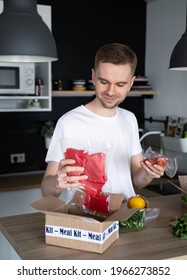 Happy Caucasian White Man Unpack Online Home Food Delivery. Box With Packed Tuna, Shrimp, Vegetables And Recipe Card On A Kitchen Background. Food Delivery Services. Dinner Set From Restaurant.