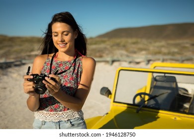 Happy caucasian woman next to beach buggy by the sea taking picture. beach break on summer holiday road trip. - Powered by Shutterstock