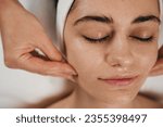 Happy caucasian woman receiving soothing mask or moisturizing cream balm, massaging face at spa salon. Daily spa morning routine.