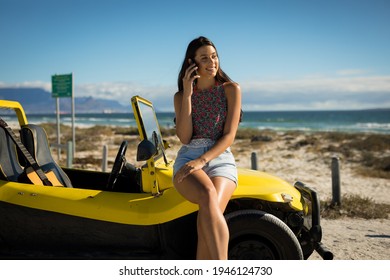 Happy caucasian woman sitting on beach buggy by the sea talking on phone. beach break on summer holiday road trip. - Powered by Shutterstock