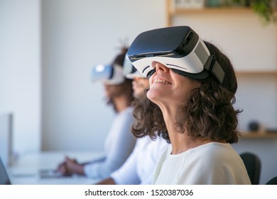 Happy Caucasian woman in VR glasses enjoying experience. Group of people testing virtual reality software. Innovation technology concept - Powered by Shutterstock