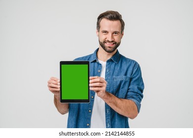 Happy caucasian young man student freelancer holding showing digital tablet with green mockup screen for ad copyspace isolated in white background