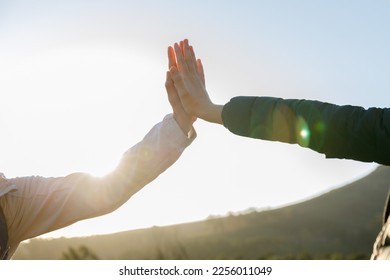 Happy caucasian young woman giving high five to female friend while hiking together in woodland during sunrise - Shutterstock ID 2256011049