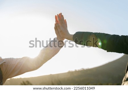 Happy caucasian young woman giving high five to female friend while hiking together in woodland during sunrise