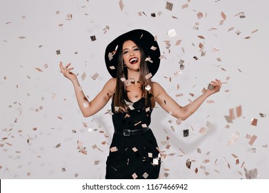 Happy Charming Brightful Female Model In Black Witch Halloween Costume On The Party Over White Background With Confeti