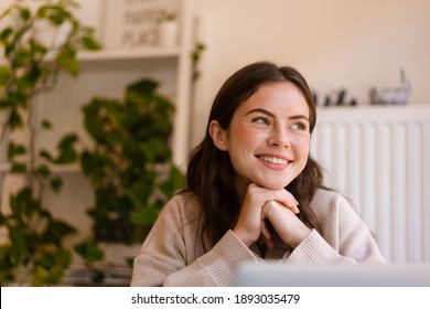 Happy Charming Girl Smiling And Looking Aside While Sitting In Cafe Indoors