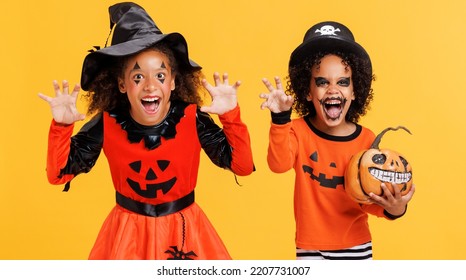 Happy Cheerful African American Kids Boy And Girl With Curly Hair In  Pumpkin Costume And Terrible Makeup  Scary Gestures And Celebrates Halloween And Laughs On Yellow Background