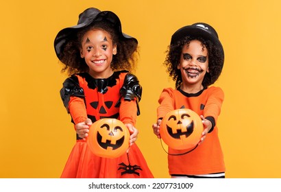 Happy cheerful african american kids boy and girl with curly hair in  pumpkin costume and terrible makeup  with basket celebrates Halloween and laughs on yellow background - Shutterstock ID 2207731009