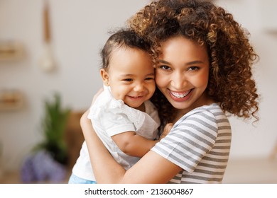 Happy, cheerful african american mother holds a laughing baby daughter in her arms. Concept of motherhood and a loving family - Shutterstock ID 2136004867