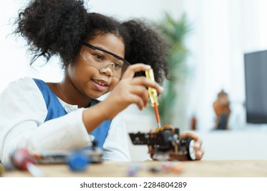 Happy cheerful American - African ethnicity girl enjoy learning to assemble a robot by herself. Creativity and thinkiing learning skill in elementary children. - Powered by Shutterstock