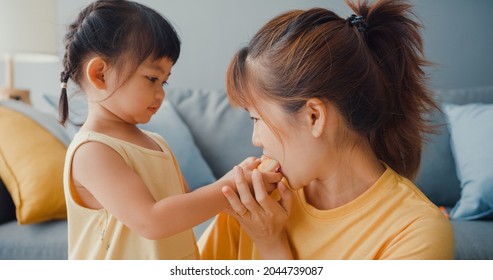 Happy Cheerful Asia Family Mom And Toddler Girl Eating Donuts And Having Fun Relax Enjoy On Couch In Living Room At House. Spending Time Together, Social Distance, Quarantine For Coronavirus.