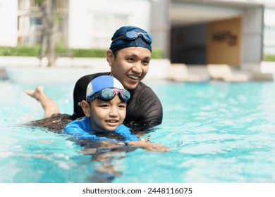 Happy cheerful Asian father and son playing and swimming together in the swimming pool, a boy enjoy playing a water with his dad. Summer and vacation activities in family. - Powered by Shutterstock