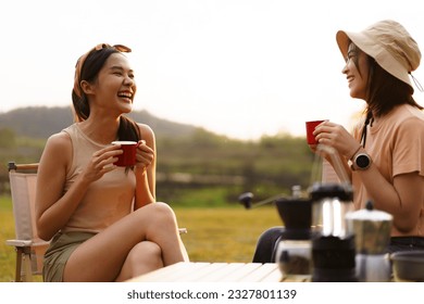 Happy cheerful Asian young women - friends camping in the lake forest and enjoy drinking a cup of tea or coffee. Female friends on a camping trip in the natural park in summer. - Powered by Shutterstock