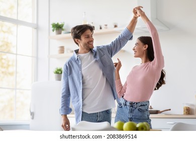 Happy cheerful attractive young husband and wife dancing and have fun together in kitchen interior, empty space. Couple enjoy domestic romantic date in own new home together on weekend and free time - Powered by Shutterstock
