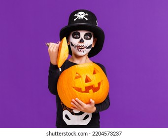 Happy cheerful boy in skeleton costume with  pumpkin  jack-o-lantern  celebrates Halloween and laughs on  bright purple background - Shutterstock ID 2204573237