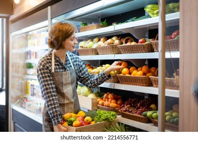 Happy cheerful caucasian grocery store staff arranging a vegetables and fruits on the shelf. Woman staff are working in food and vegetable hypermarket or grocery store. - Powered by Shutterstock