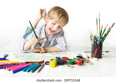 Happy cheerful child drawing with brush in album using a lot of painting tools. Creativity concept. - Powered by Shutterstock